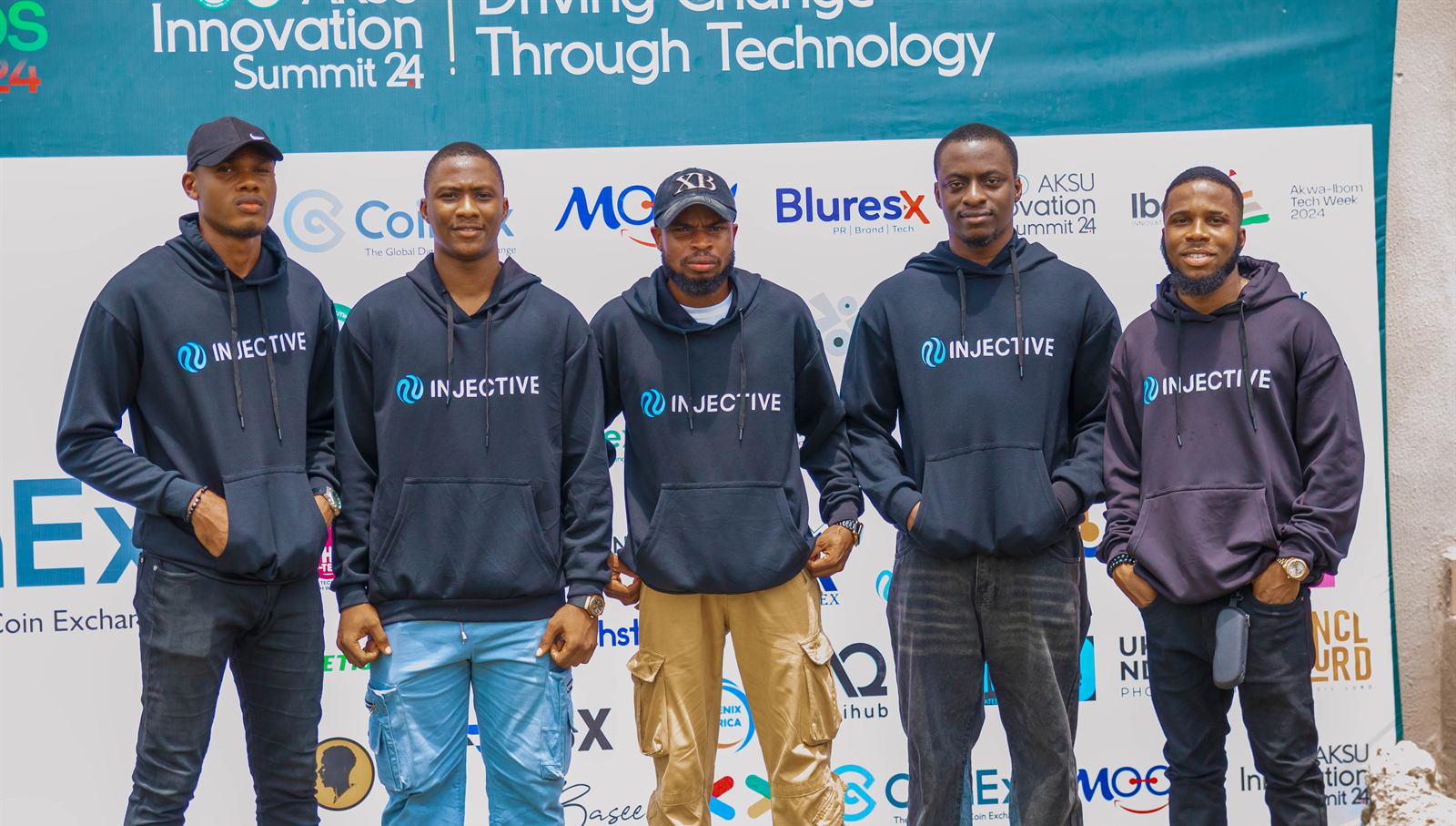 A team in matching hoodies in front of the sponsor backdrop